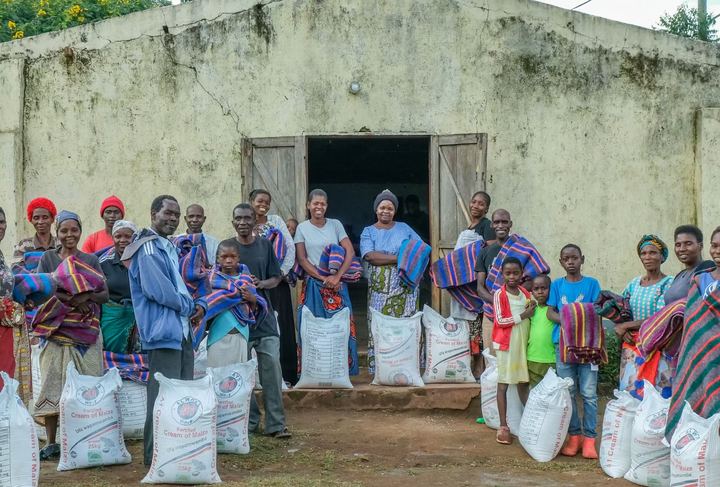 A community group standing with sacks of food outside a building