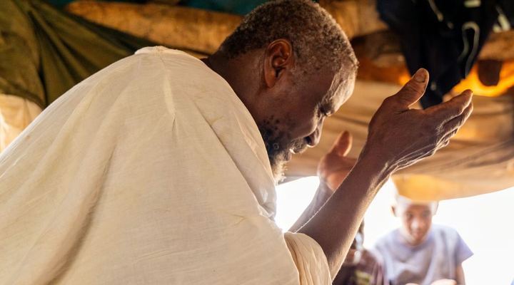 A man praying with his hands raised to his face