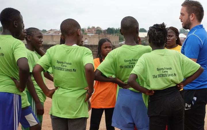 A sports team in green shirts gathered with their coach