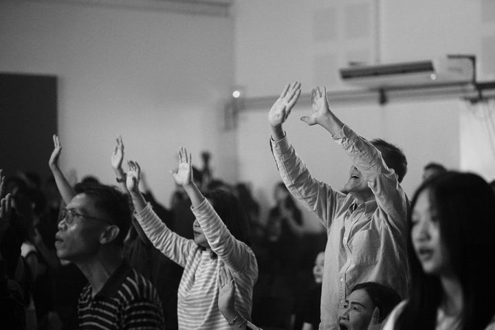Black and white photograph of hands raised in worship