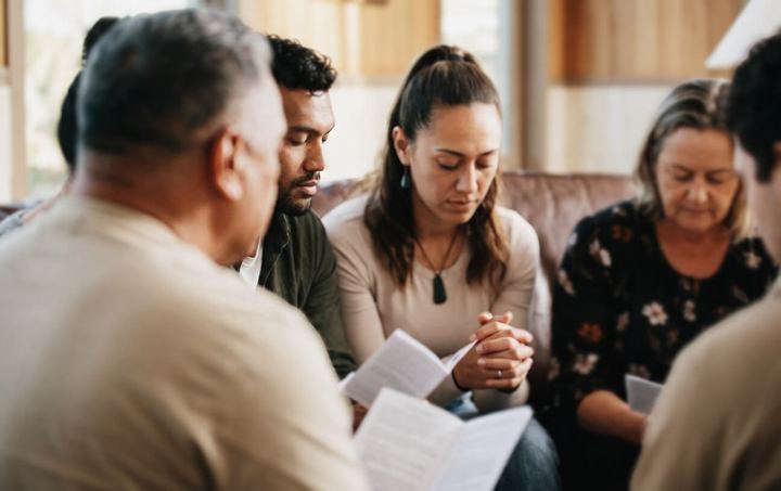 A small group praying together in a living room